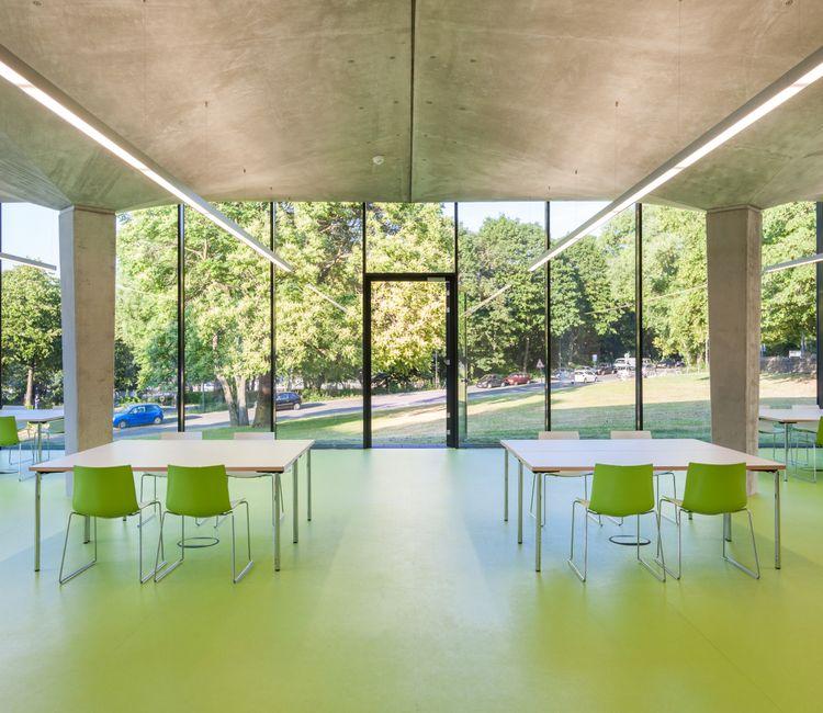 Innenraum des Pavillons mit symmetrischer Möblierung und Ausblick ins Grüne.