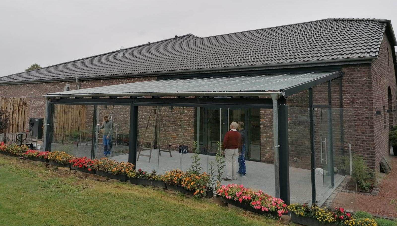 Zwei Personen betrachten die fast fertiggestellte Glasüberdachung am Backsteingebäude.