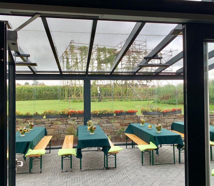 Durch das transparente Glasdach und die Seitenverglasung eröffnet sich ein weiter Blick in den Garten.