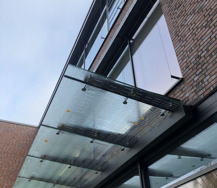 Detailansicht des Glasvordachs mit Halterungen über dem Eingang
