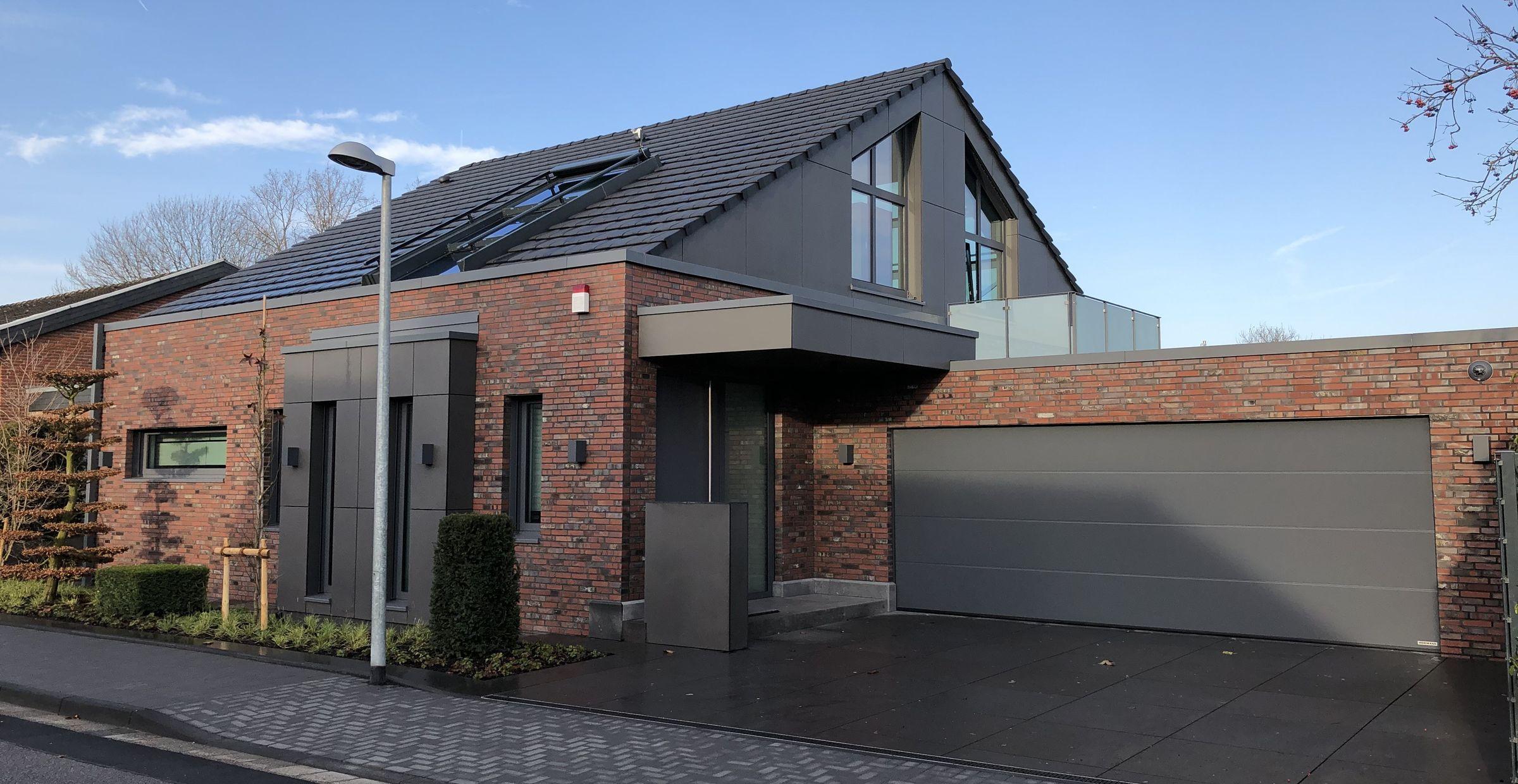 Modernes Einfamilienhaus mit Ziegelfassade und großem Garagentor