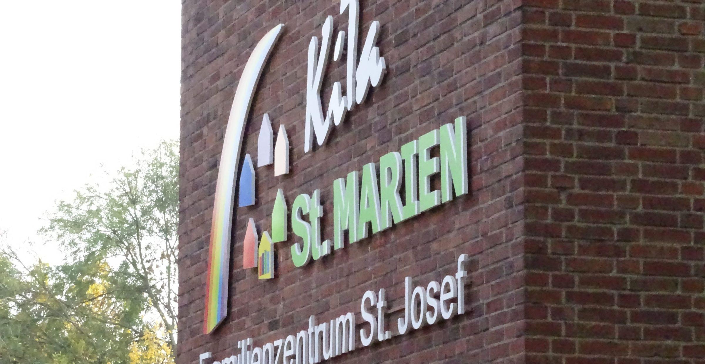 Nahaufnahme der neuen bunten KiTa-St. Marien-Beschriftung am Glockenturm.