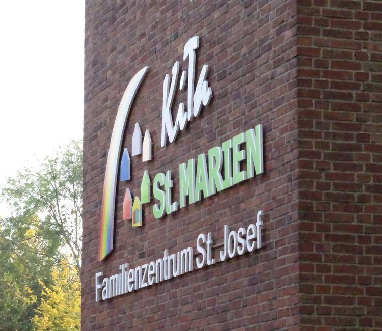 Nahaufnahme der neuen bunten KiTa-St. Marien-Beschriftung am Glockenturm.