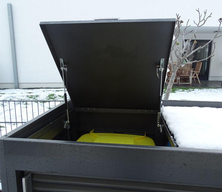 Nahaufnahme der geöffneten Müllbox mit Blick auf den gelben Abfallbehälter.