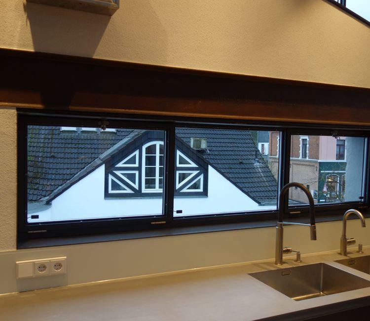 Blick auf das lange Fensterband über der Küchenzeile mit Blick auf ein Fachwerkhaus.