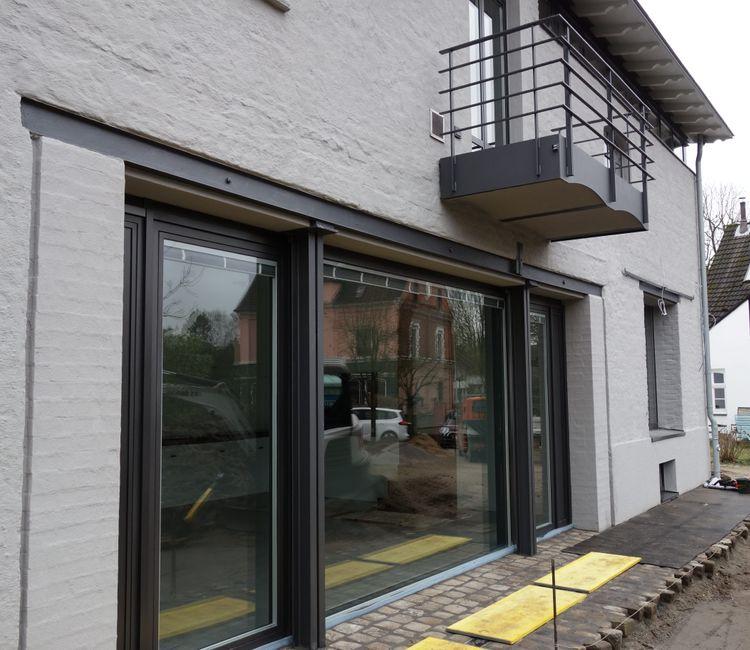Außenansicht mit großen Schiebetüren, Balkon und traditioneller weißer Putzfassade.