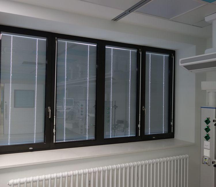 Fensterfront in einem Behandlungsraum mit innenliegendem Jalousiesystem.