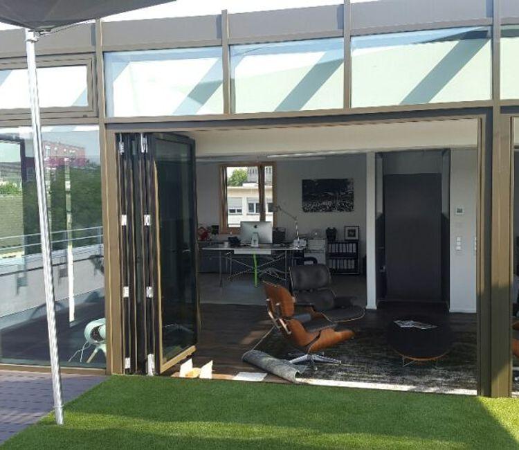 Geöffnete Glasfaltwand mit Zugang zur Dachterrasse des Hellweg-Quaders, Blick in ein stilvoll eingerichtetes Büro.