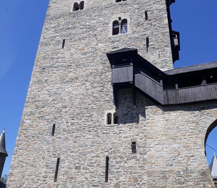 Außenansicht des hohen Bergfrieds von Schloss Burg mit gut sichtbaren Fenstern und Erkern.