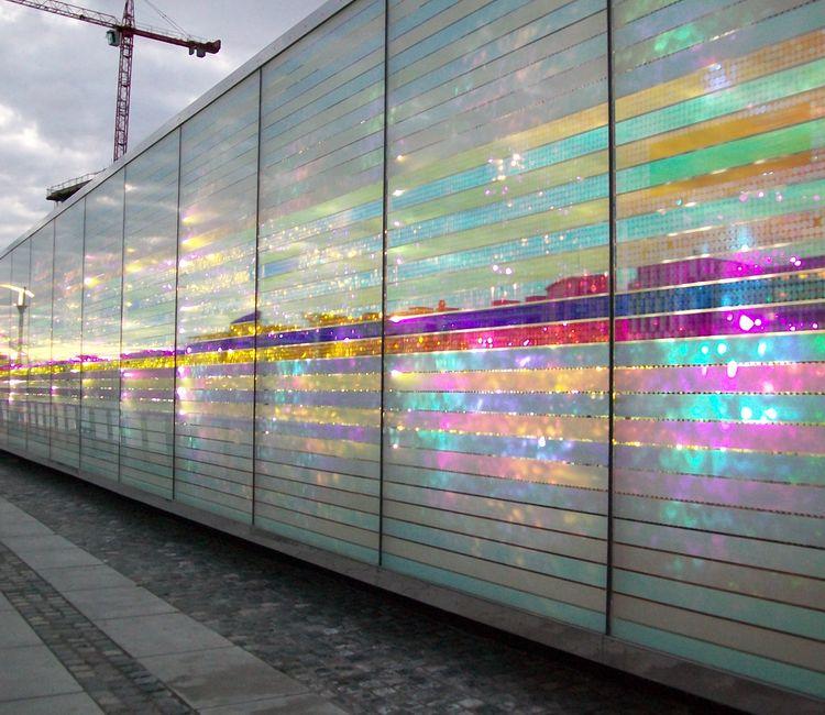 Glasfassade im Abendlicht mit leuchtenden Farben und spiegelnden Effekten.