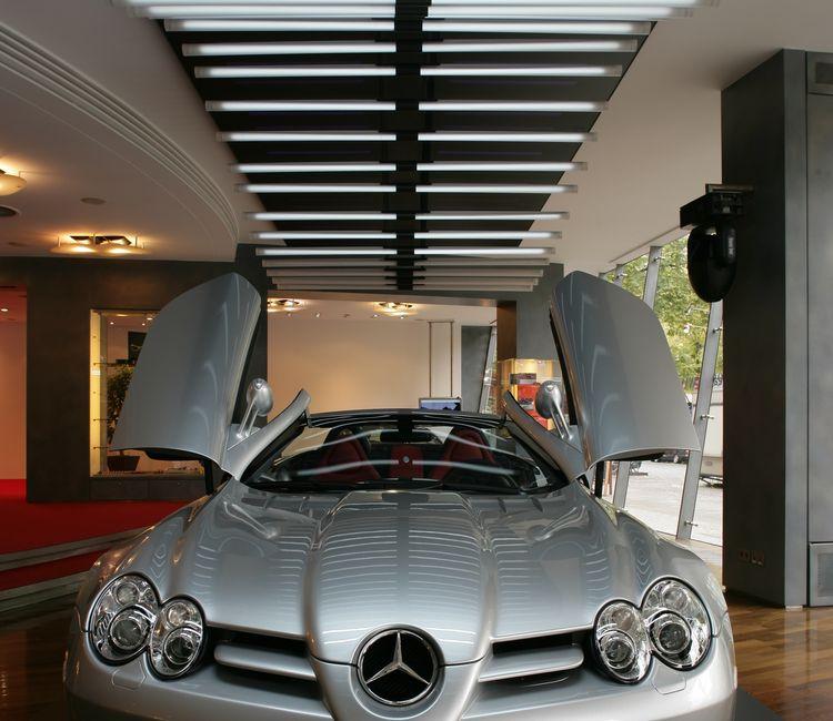 Frontansicht eines Mercedes SLR McLaren mit geöffneten Flügeltüren unter Lichtstreifen