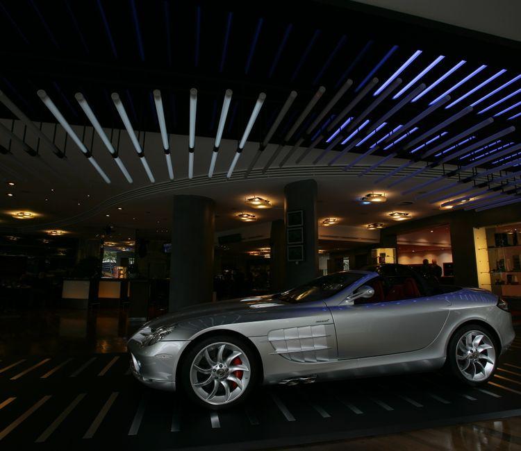 Silberner Sportwagen im Showroom bei abgedunkelter Lichtinstallation in Blau und Weiß
