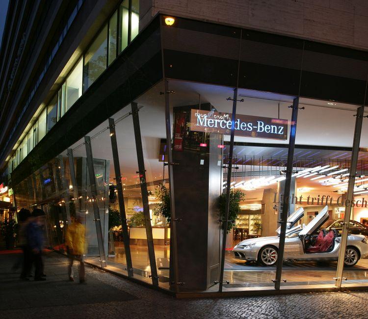 Außenansicht des Mercedes-Benz Showrooms bei Nacht, mit verglaster Fassade und beleuchtetem Innenraum.