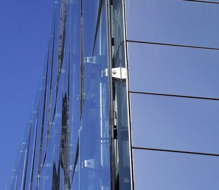 Detailaufnahme der Befestigungselemente einer Glasfassade mit seitlichem Blick auf das Fassadensystem.